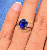 Load image into Gallery viewer, Blue sapphire gemstone ring on a person's finger with a blue denim background
